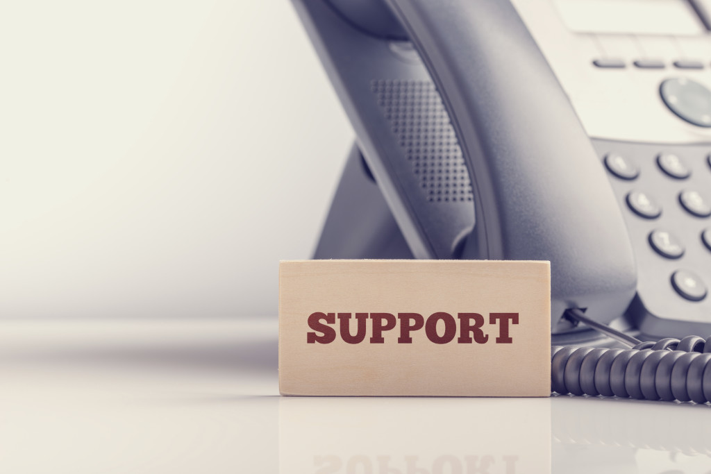Retro image of business telephone support concept with a small wooden sign saying - Support